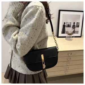 Detail view of black lychee-textured leather saddle bag with gold metal buckle