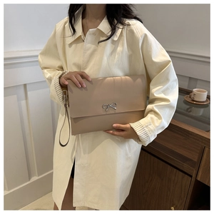 Detail of beige envelope clutch bag with silver metal bow clasp and wrist strap