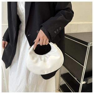 Detail of a minimalist white crescent hobo bag with gold hardware held by a model