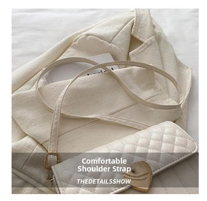 Close-up of white quilted crossbody bag with heart-shaped gold lock and fine stitching