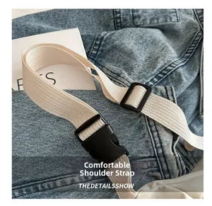 Close-up of adjustable woven shoulder strap with black plastic buckle on denim background