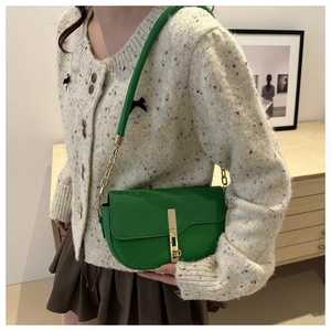 Detail of green saddle bag with lychee pattern leather and metallic buckle strap