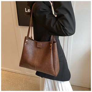 Détail d'un sac cabas en cuir marron sur modèle avec gaufrage FASHION et couture verticale