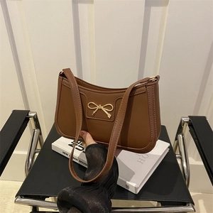 Borsa a spalla in pelle PU marrone con fiocco in metallo dorato su sedia nera