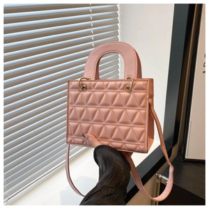 Detail of light pink quilted handbag with triangular stitching and gold hardware