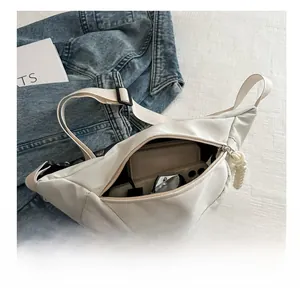 Internal storage view of white half-moon chest bag with wallet, sunglasses and accessories