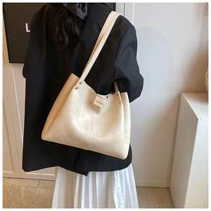 Détail d'un grand sac cabas crème avec rivets dorés porté par un mannequin
