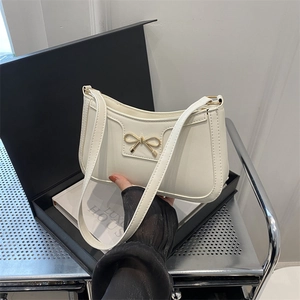 Borsa a spalla minimalista crema con fibbia a fiocco dorato su scatola regalo
