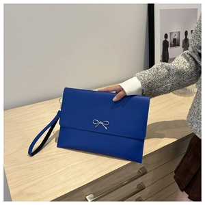 Detail of royal blue leather envelope clutch bag with silver bow buckle and wristlet strap