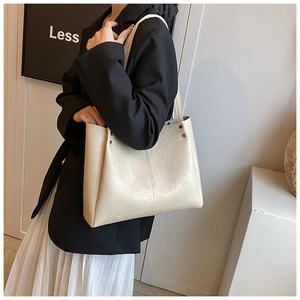 Détail d'un grand cabas en cuir crème avec rivets porté pour un look de bureau chic