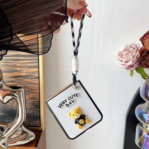 Detail of Galaxy Z Flip case featuring a 3D teddy bear and black-and-white lanyard