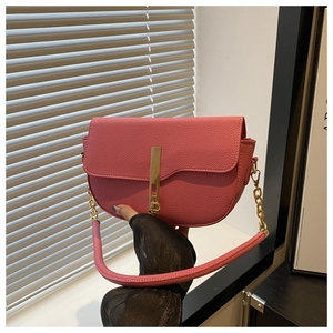 Close-up of pink litchi grain leather saddle bag with gold metal lock and chain strap