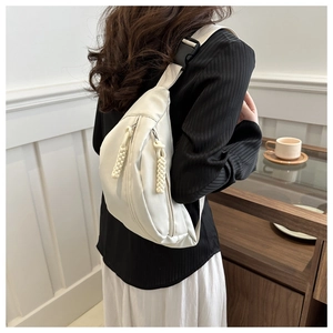Detail of minimalist beige half-moon chest bag with braided rope zipper and black strap