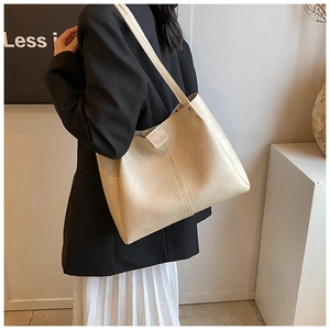 Détail du grand sac cabas beige en similicuir texturé porté à l'épaule avec étiquette