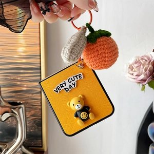 Detail of yellow charm with bear mascot and orange crochet pendant for phone case