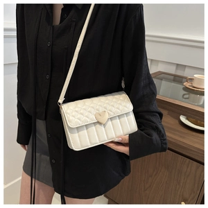 Detail of white crossbody bag with golden heart buckle and diamond quilted pattern