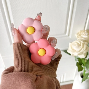 Matte flower phone grip in soft pink tones shown held by a hand on a clean background