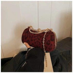 Close-up of leopard print burgundy velvet evening clutch with gold chain and rhinestone clasp