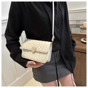 Close-up of cream crossbody bag featuring a golden heart lock and quilted stitching detail