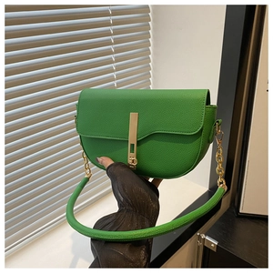 Close-up of vibrant green saddle bag with lychee texture leather and gold metal buckle