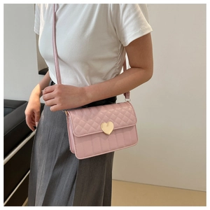 Detail of pink quilted shoulder bag featuring gold heart-shaped clasp and chain strap