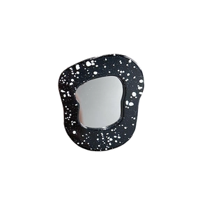 Détail d'un miroir de téléphone irrégulier avec cadre noir et motif d'éclaboussures blanches