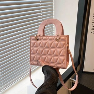 Pink quilted handbag with triangular stitching and gold hardware on top handle