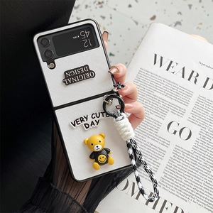 Detail of white leather phone case for Samsung Z Flip with cute bear charm and hand strap