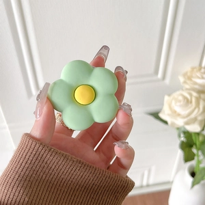 Close-up of a matte green flower-shaped pop socket with a yellow center being held
