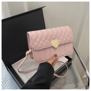 Detail of pink quilted shoulder bag featuring a gold heart-shaped metal lock and texture