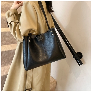 Détail d'un grand sac cabas noir à texture froissée et rivets métalliques porté par un mannequin