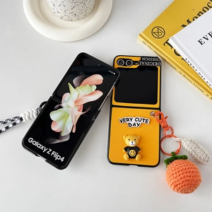 Cute bear Galaxy Z Flip 4 case in yellow with orange crochet ball charm and hand strap