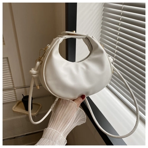 Détail du sac demi-lune blanc avec fermoir doré et texture en similicuir lisse