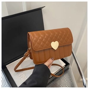 Detail of brown quilted crossbody bag featuring a golden heart-shaped metal buckle