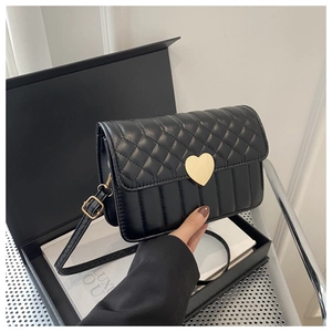 Close-up of quilted black crossbody bag with a prominent golden heart-shaped metal clasp