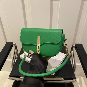Modern green pebble leather saddle bag with gold hardware on a minimalist chair