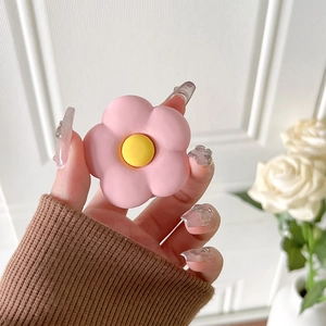 Close-up of hand holding a pink matte flower grip stand on phone back with yellow center