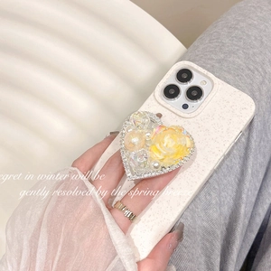 Detail of heart phone grip with yellow resin rose, pearls, and crystals on a beige case