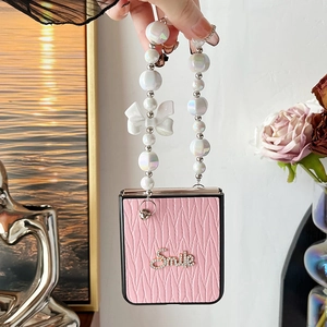 Detail of pink leather folding phone case with diamond Smile letters and pearl chain