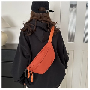 Detail of bright orange waterproof nylon waist bag with black adjustable strap and woven zipper