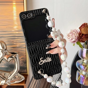 Detail of black pleated leather phone case with Smile lettering and pearl lanyard