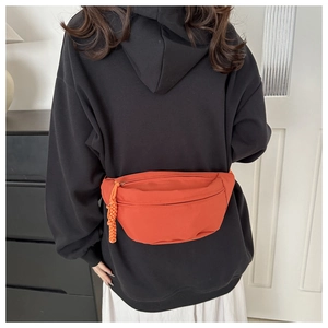 Detail of orange nylon sports fanny pack with textured surface and woven rope zipper pull