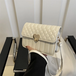 Quilted cream crossbody bag with golden heart buckle and elegant rhombic stitching