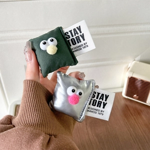 Close-up of pillow-shaped plush phone stands with big eyes in green and silver colors