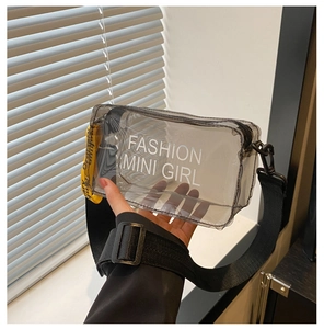 Détail du sac bandoulière en PVC gris transparent avec texte blanc et étiquette jaune