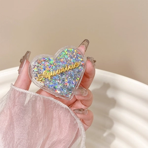Detail of heart-shaped phone grip with glitter and Aquarius lettering held in hand