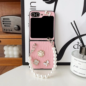 Détail de la coque rose texture cuir avec chaîne en perles et breloques sur un bureau