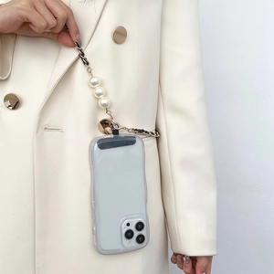 Crossbody phone case with pearl and leather-woven metal chain worn over a white suit
