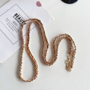 Detail of light gold chain woven with brown leather and sturdy metal lobster clasps