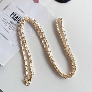 Close-up of a luxury gold metal and white leather interwoven crossbody phone chain strap